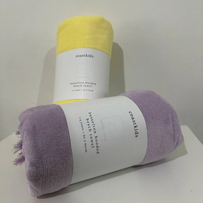 two rolled-up towels, one yellow and one purple, with labels on a white surface.