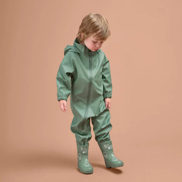 Child wearing a green raincoat and boots on a beige background