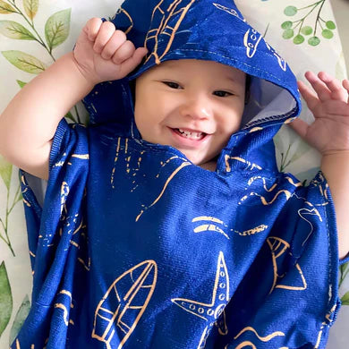 Child wearing a blue hooded towel with gold patterns on a white background