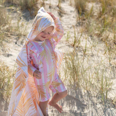 Child in a colorful towel on a sandy beach
