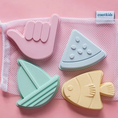 Set of silicone bath toys shaped like a hand, leaf, sailboat, and fish on a pink background with a mesh storage bag.