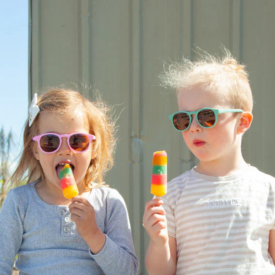 Two children enjoying colorful popsicles outdoors.