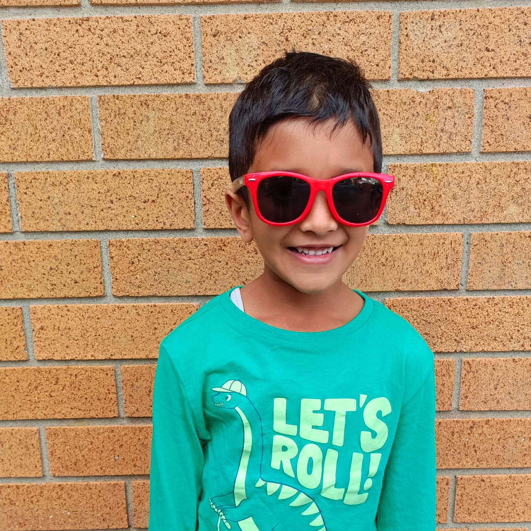 Child wearing red sunglasses and a teal shirt with &